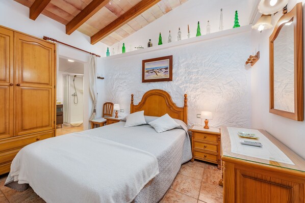 A bedroom with a wooden bed, a nightstand, a dresser, and a shower area. - Villa Bon Redos by JS Villas (Pollensa)