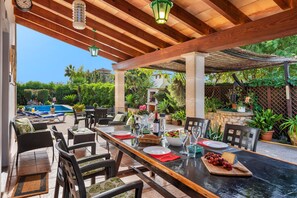 An outdoor patio with a dining table set for four, surrounded by wicker chairs and a pergola overhead. - Villa Bon Redos by JS Villas (Pollensa)