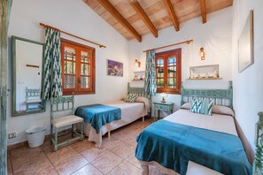 A bedroom with two beds, a chair, a nightstand, a lamp, and a painting on the wall. - Villa Bon Redos by JS Villas (Pollensa)
