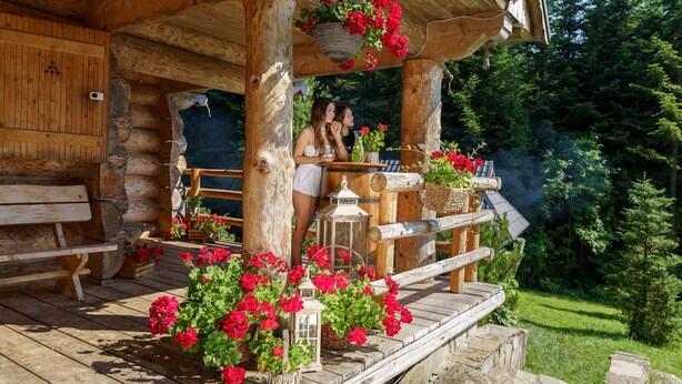 Eine rustikale Holzhütte mit einer Veranda, geschmückt mit roten Blumen und Laternen.
