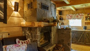 Ein gemütliches Blockhaus-Interieur mit Kamin aus Stein, Holzmöbeln und einer Küchenzeile.