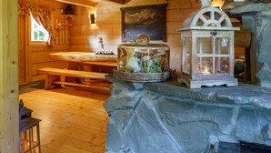 Ein rustikales Holzinnere mit Kamin aus Stein, einer hölzernen Bank und einer Laterne.