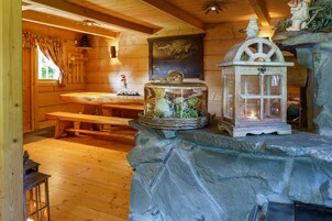Un interior rústico de madera con una chimenea de piedra, un banco de madera y un farol.