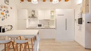 A modern kitchen with white cabinetry, a wooden ceiling, and pendant lighting. - Luxury modern Studio in historic district (Cagliari)