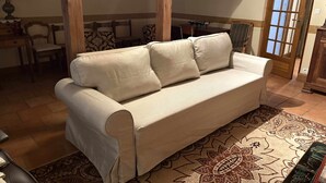 A beige sofa with a patterned rug, wooden beams, a dining table, chairs, and a door with glass panels. - Château region/Sancerre Loire Valley large family house! Spacious w/courtyard! (Pierrefiette sur Sauldre)