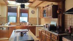 A kitchen with wooden cabinets, a large island, and a hanging pot rack. - Château region/Sancerre Loire Valley large family house! Spacious w/courtyard! (Pierrefiette sur Sauldre)