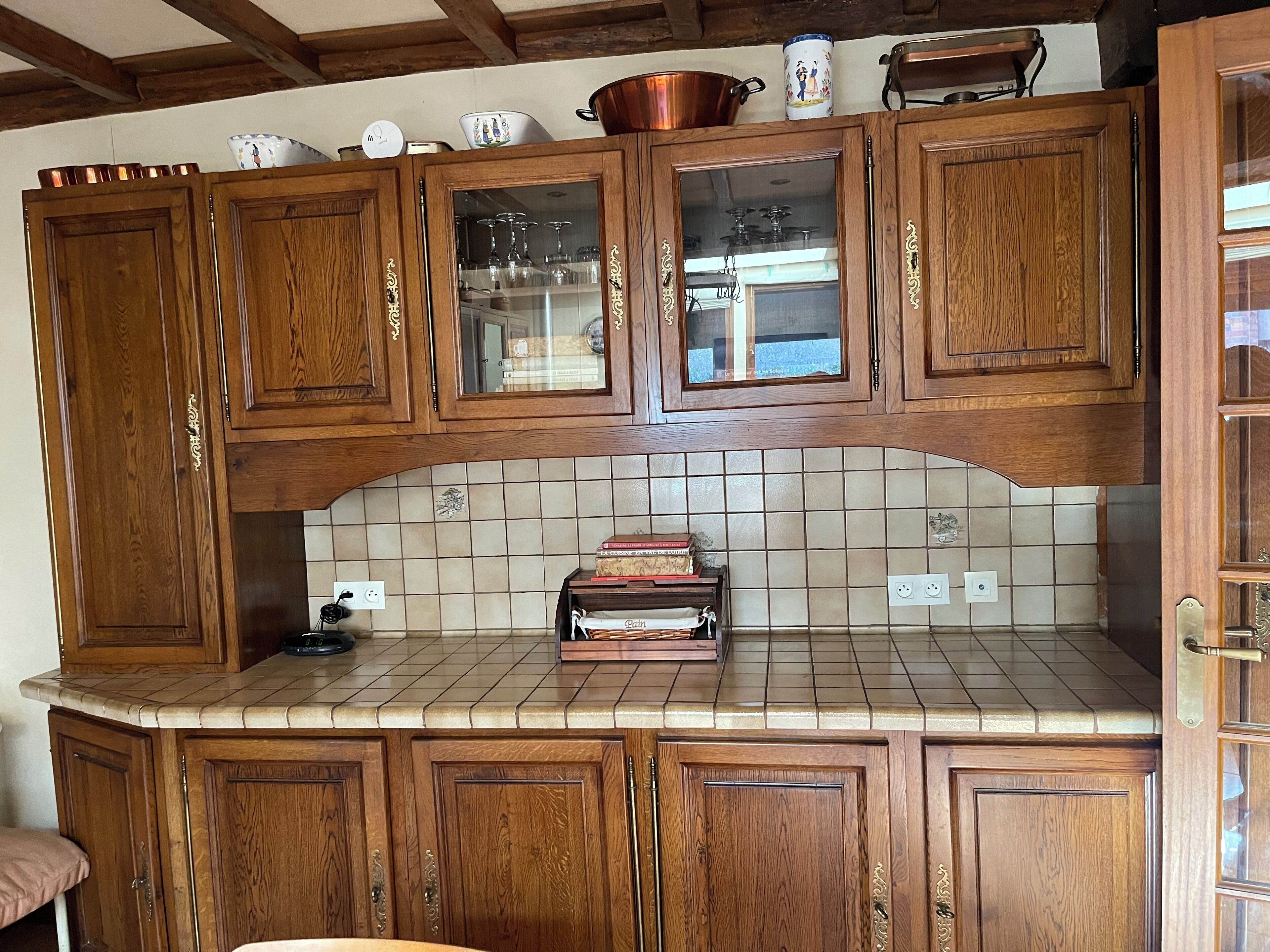 Een keuken met houten kastjes, een betegelde spatwand en een aanrecht met een broodrooster.
