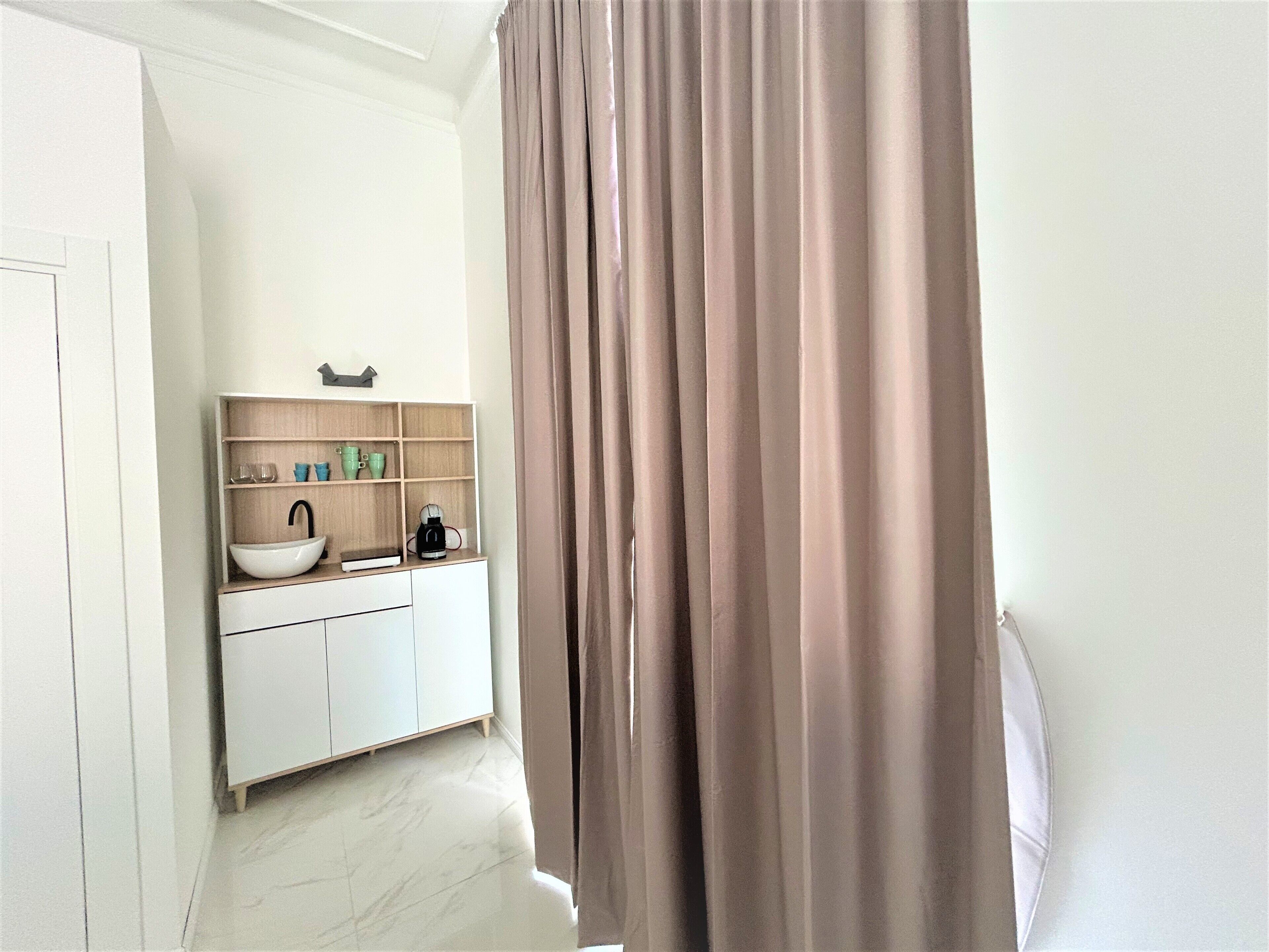 A bathroom with a white sink, a mirror, and a beige curtain.