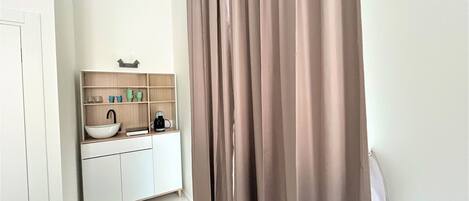 A bathroom with a white sink, a mirror, and a beige curtain.