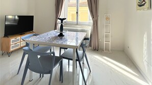Uma área de refeições com mesa, cadeiras, uma TV e um radiador.
