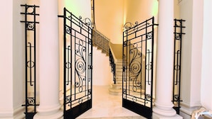 Uma escadaria imponente com grades de metal preto ornamentadas e degraus de mármore branco.