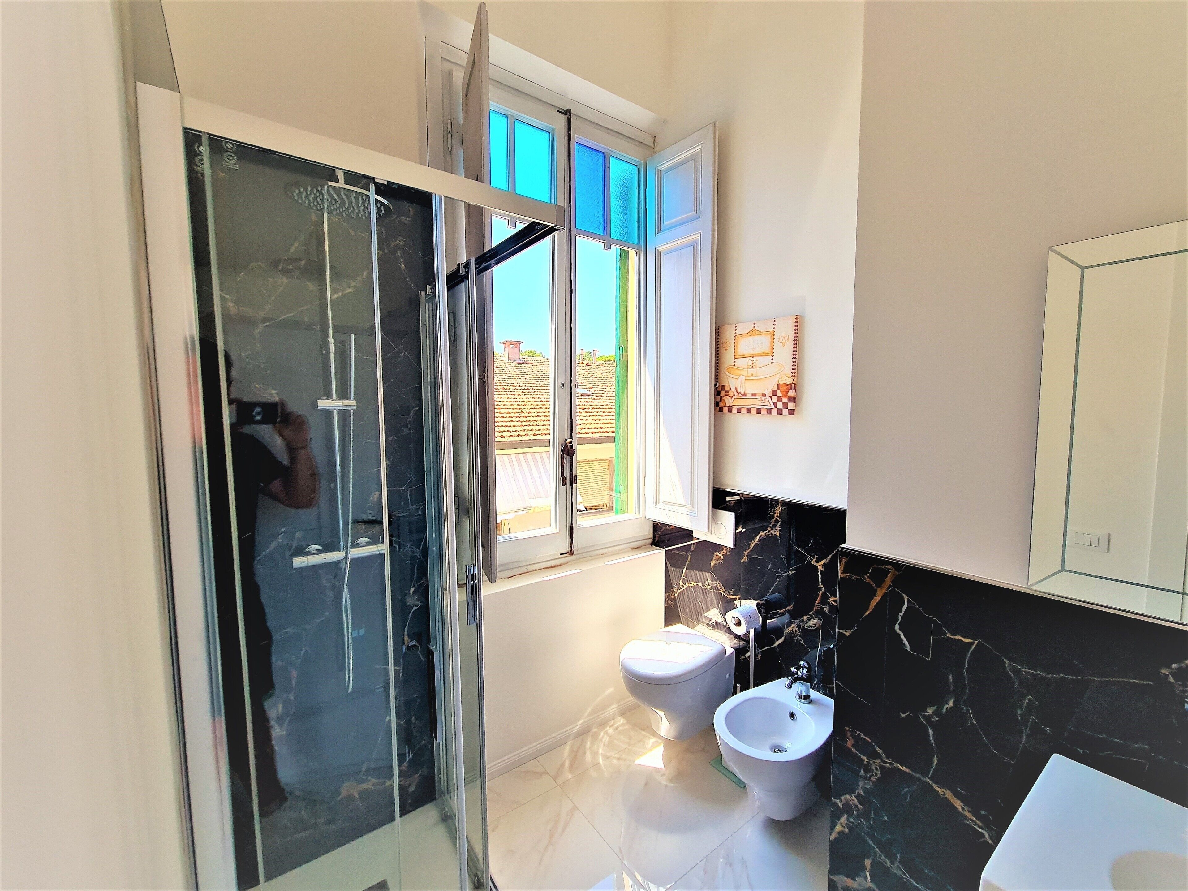 Une salle de bain moderne dotée d’une douche à parois de verre, de toilettes et d’un bidet.