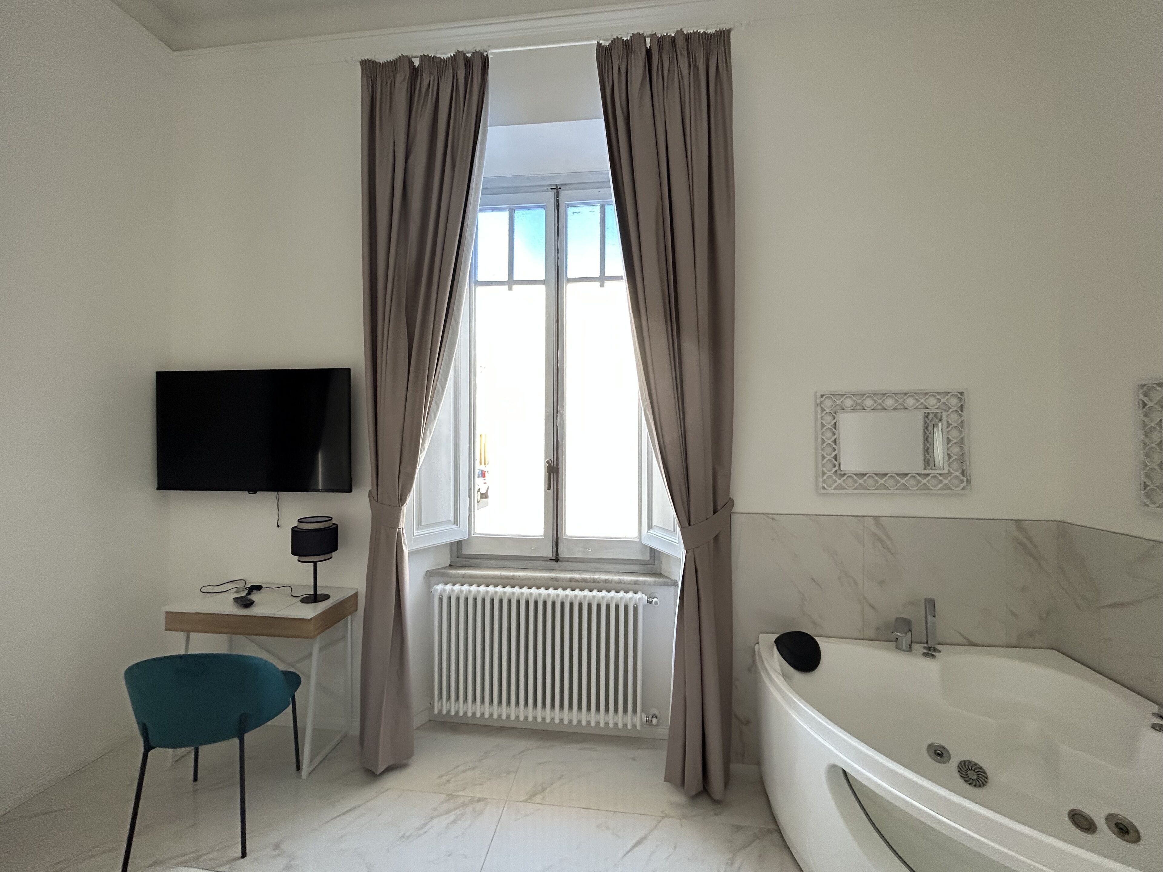Une salle de bain moderne équipée d’une baignoire, d’un téléviseur, d’un bureau et d’une chaise.