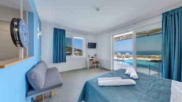 Habitación de hotel con cama, escritorio, silla, televisor y vista al mar.
