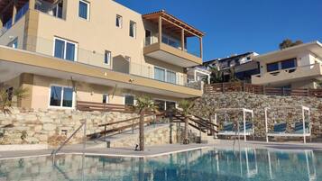 Un hotel moderno con zona de piscina, paredes de piedra y varios balcones.