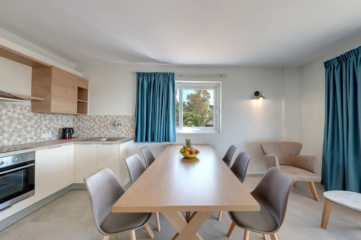 Une cuisine moderne avec un coin repas, une vue par la fenêtre et un panier de fruits sur la table.