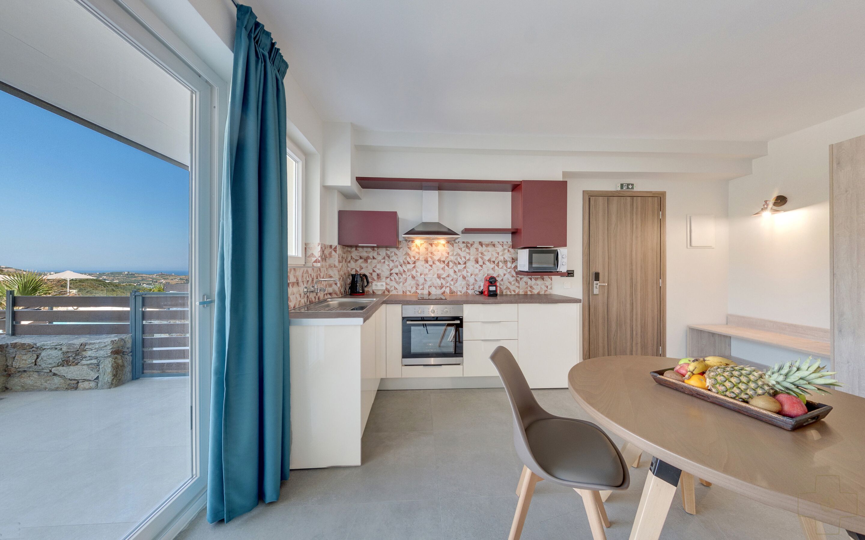 Et moderne køkken med spiseplads, havudsigt og en balkon med stenvæg.