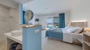 A hotel room with a bed, a bathroom with a sink, a mirror, and a view of the sea.