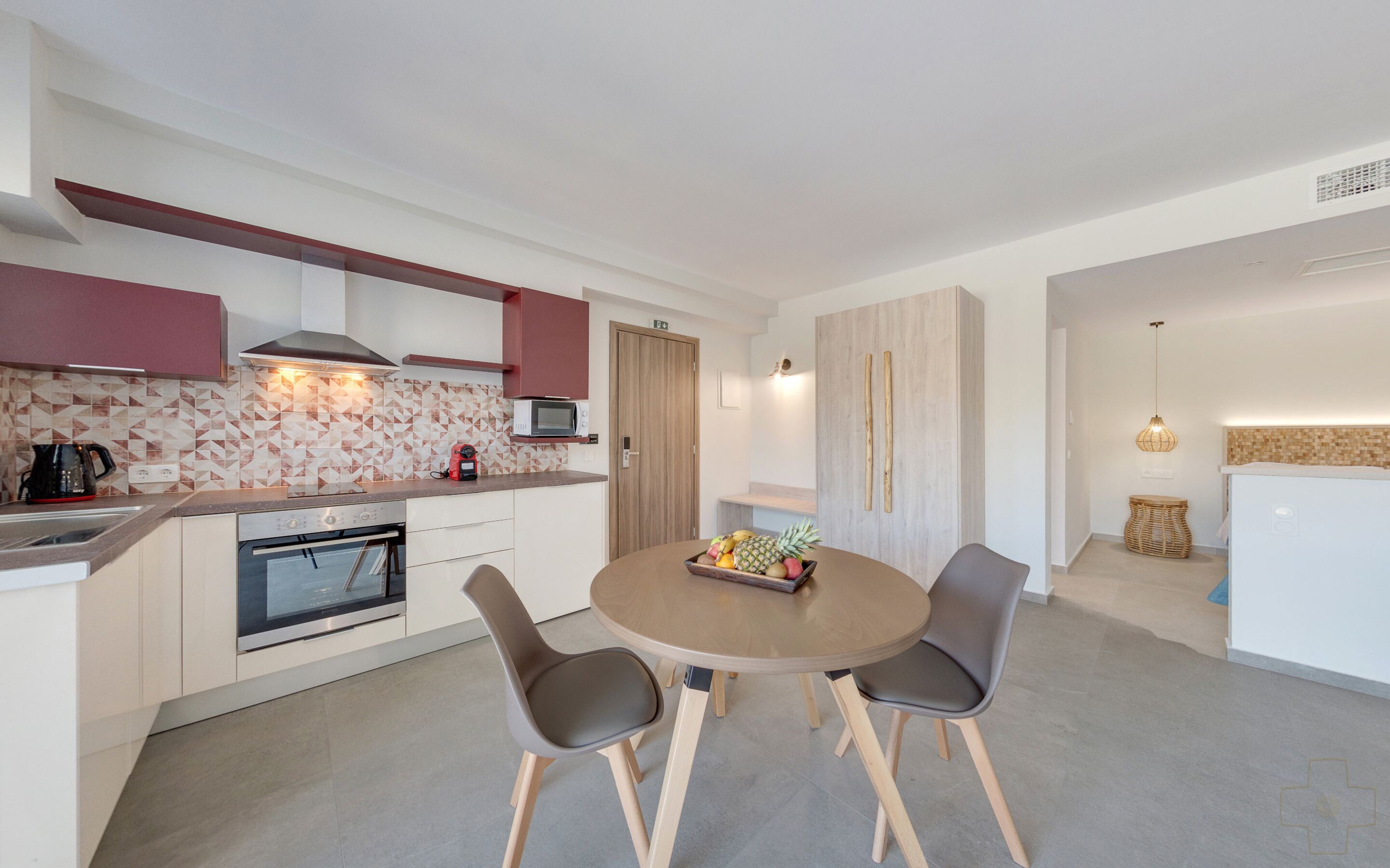 Una cocina moderna con horno integrado, microondas y un comedor con una mesa redonda y dos sillas.