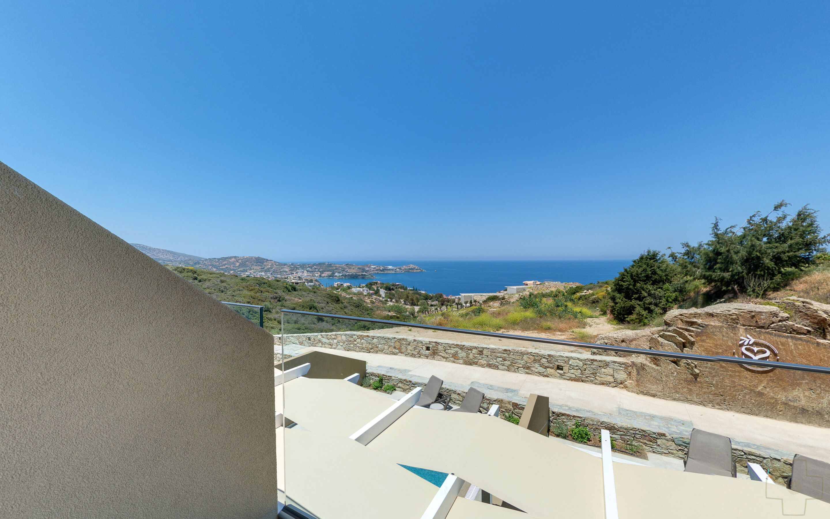 A balcony with a view of the sea and distant buildings.