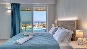 A bedroom with a bed, a nightstand, a lamp, and a view of the ocean through a sliding glass door.
