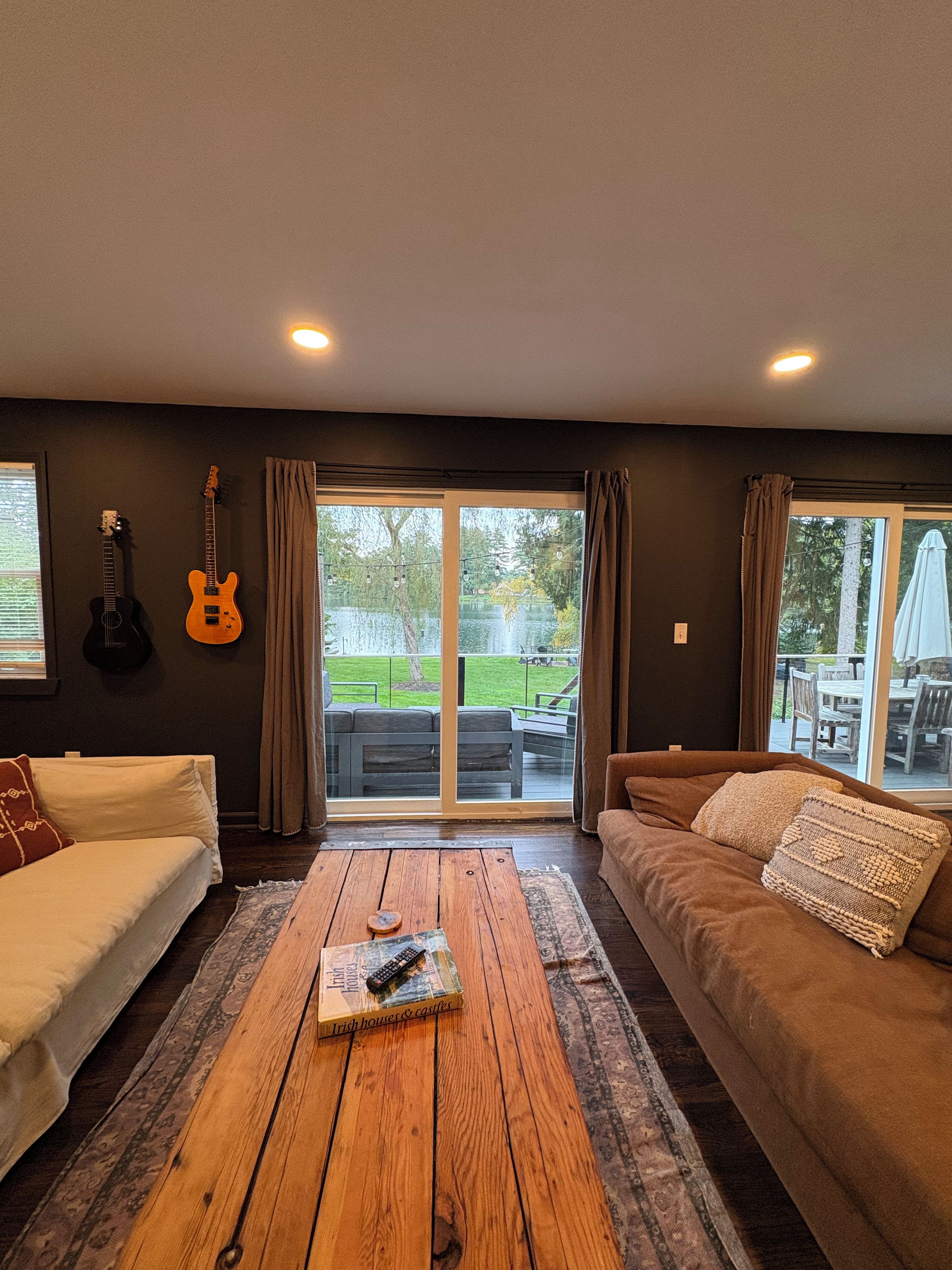 Una sala de estar con dos sofás, una mesa de centro y una guitarra colgada en la pared.