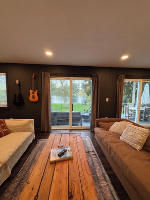 A living room with two sofas, a coffee table, and a guitar on the wall.