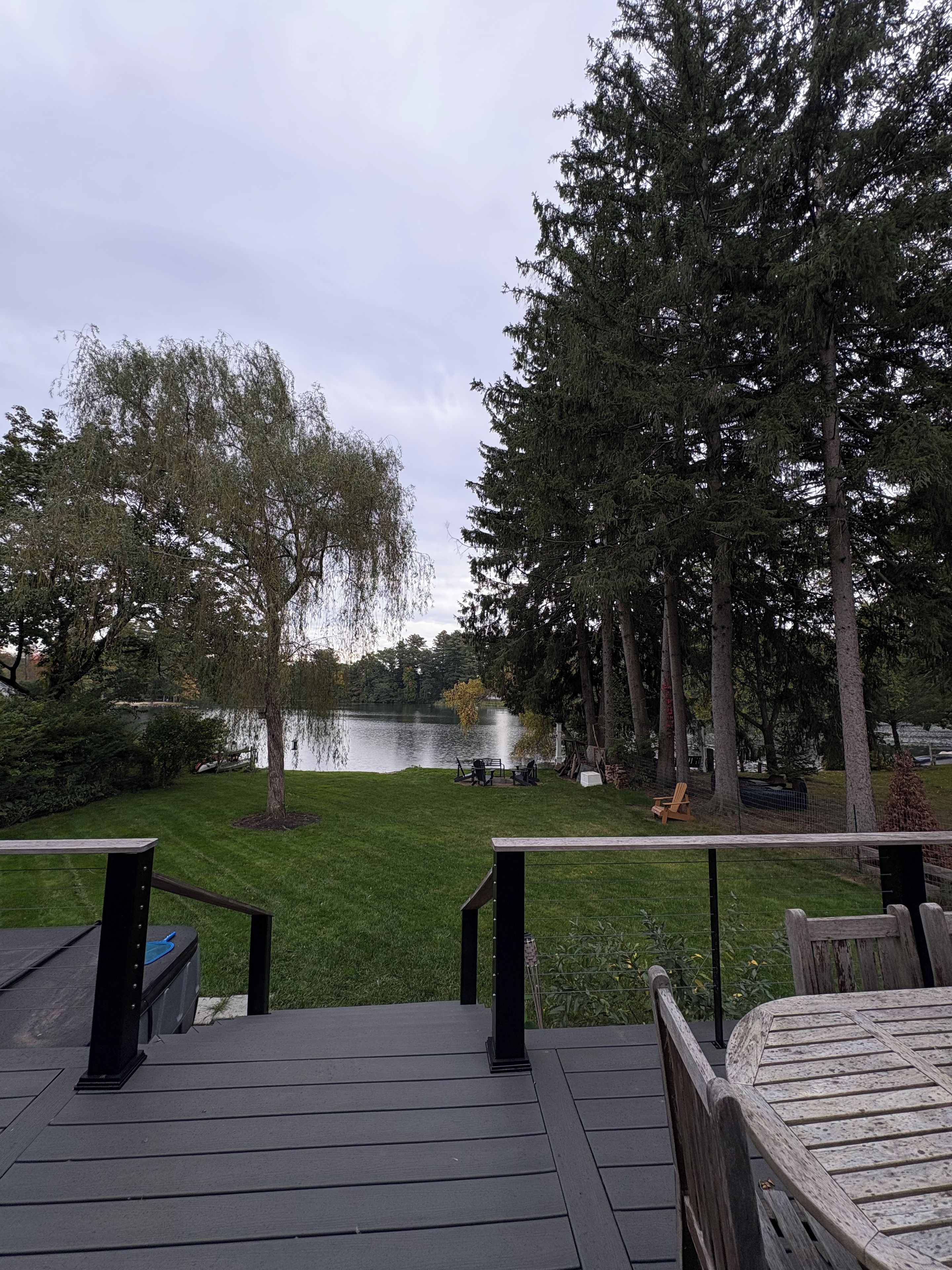Eine Terrasse mit Blick auf einen See, umgeben von Bäumen und einer Rasenfläche.