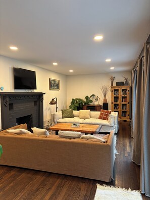 A living room with a fireplace, sofa, coffee table, and a television mounted on the wall.
