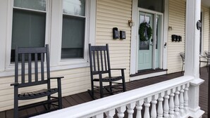 A porch with two wooden chairs, a green door, and a white railing. - TROY, NY Studio near Emma Willard (Troy)