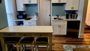 A compact kitchen with white cabinets, a microwave, a coffee maker, and a toaster. There is a small dining table with two chairs. - TROY, NY Studio near Emma Willard (Troy)