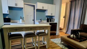 A compact living space with a kitchenette, a dining area with stools, and a sofa. - TROY, NY Studio near Emma Willard (Troy)