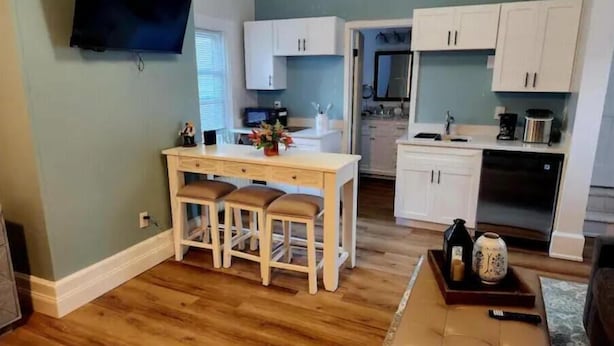 A modern kitchen with a central island, white cabinets, and a flat-screen TV mounted on the wall. - TROY, NY Studio near Emma Willard (Troy)