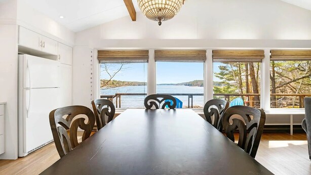 A dining area with a long table and chairs, large windows with a view of the water, and a chandelier. - Edgecomb Maine.  Close to Boothbay & Wiscasset.  Very private and relaxing. (Edgecomb)