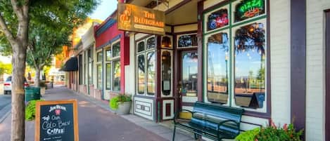 Un escaparate con un letrero que dice 'The Bluegrass Coffee & Brewing Lounge' y un letrero de neón que anuncia 'Pizza'.