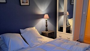 Una cama bien hecha con ropa de cama blanca en una habitación con pared azul oscuro.