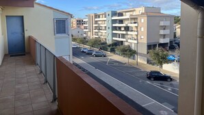 En balkon med udsigt over en boligvej og høje bygninger.