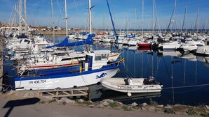 En lysthavn med mange sejlbåde i havnen, en lille motorbåd og en klar blå himmel.