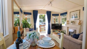 A dining area with a table set for four, a television, and a fireplace. - 25 Foxburrow Hang (Great Yarmouth)