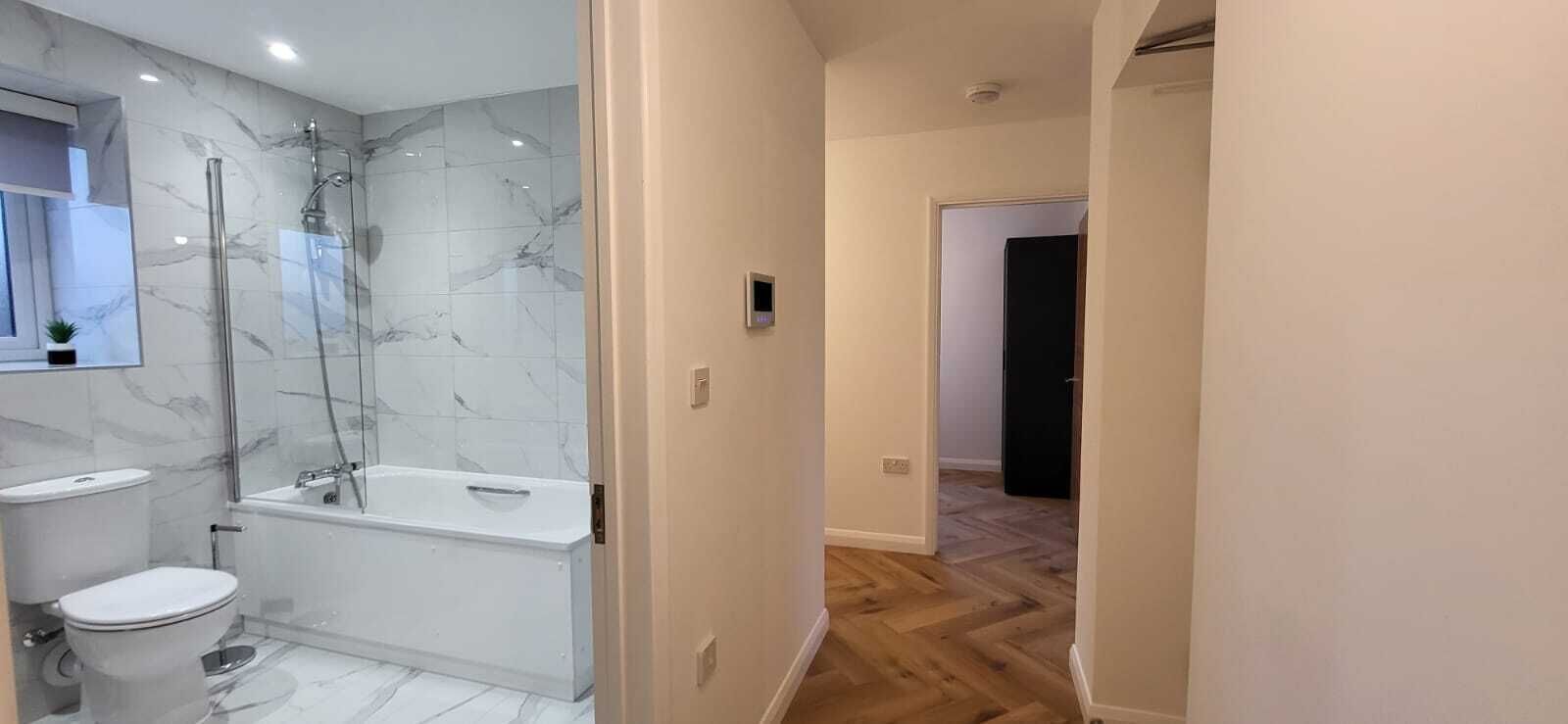 A modern bathroom with a glass-enclosed shower, a white toilet, and a bathtub.