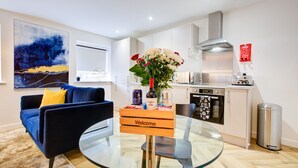 A modern living room with a glass coffee table, a blue sofa, and a "Welcome" sign. - Hybrid Resi - Mitcham  (Mitcham)
