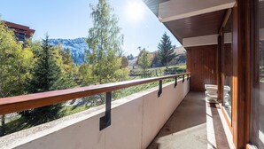 Un balcon doté d’une balustrade en bois, d’où l’on peut admirer un paysage montagneux.
