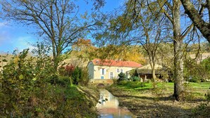 A rural house with a red roof, surrounded by trees and a small stream. - Le Moulin de L'Isle - Maison chaleureuse (L'Isle-Bouzon)