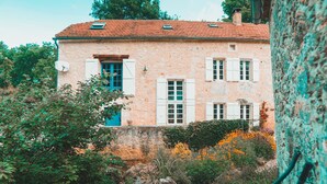 A stone building with a red-tiled roof, white shutters, and a blue door. - Le Moulin de L'Isle - Maison chaleureuse (L'Isle-Bouzon)