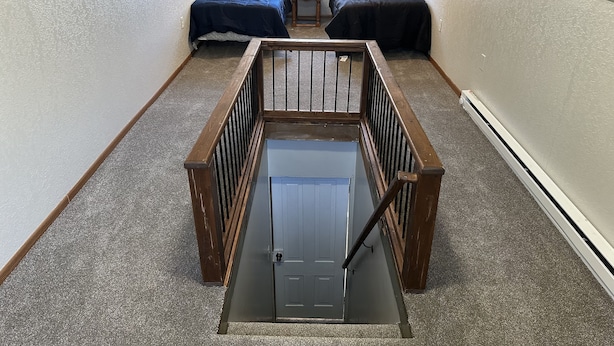 A narrow attic bedroom with two beds, a small table, and a window.