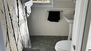 A bathroom with a toilet, a window, a towel rack, and a shower curtain.