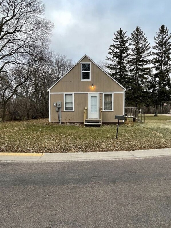 A small, single-story house with a gabled roof, a front porch, and a mailbox.