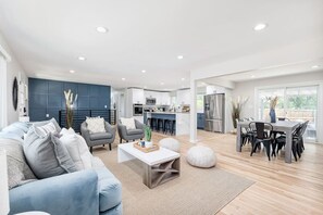 Un salon moderne comprenant un canapé, des fauteuils, une table basse et un coin repas avec une table et des chaises.