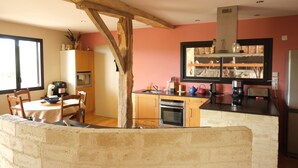 Une cuisine avec des poutres en bois, un coin repas avec des chaises et une table, et un réfrigérateur.