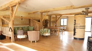 Un intérieur rustique avec des poutres apparentes, une cheminée en pierre et un coin repas doté de meubles en bois.